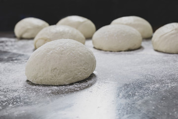 Ball of pizza dough on table with dusting of flour.