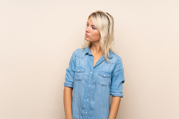 Young blonde woman over isolated background looking side