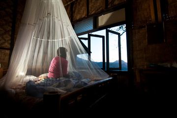 beautiful woman Sit and watch the morning scenery, Inside the mosquito net, To prevent mosquitoes.