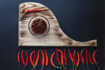 Hot red pepper lies on a cutting board on a black background. spicy Red Pepper Paprika Sauce