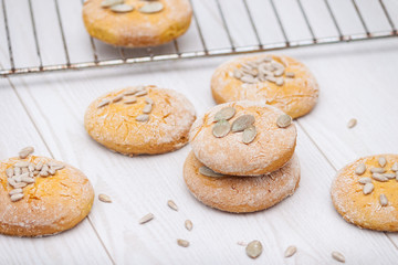 Tasty pumpkin cookies or biscuits with seeds on white wooden background.