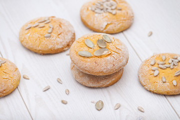 Tasty pumpkin cookies or biscuits with seeds on white wooden background.