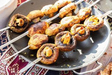 Grilled appetizing mushrooms on metal skewers