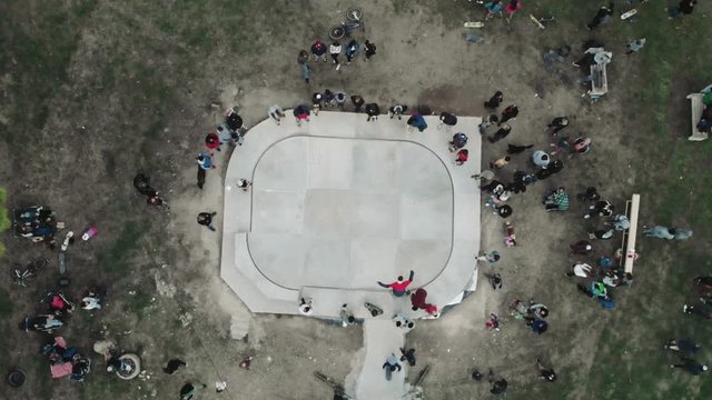 Skateboarders with friends in skate-park jumping in the halfpipe and on the other ramp, aerial view, 4k.