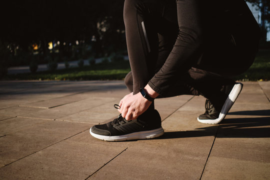 Close up spoty man tying shoelaces on sneakers during morning run in park