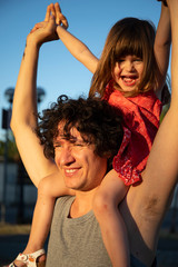 Naklejka premium Young father with little daughter on his shoulders at sunset