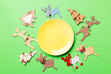 Top view of empty plate and New Year decorations on colorful background. New year serving for festive dinner. Reindeer and Christmas tree. Holiday family dinner concept.