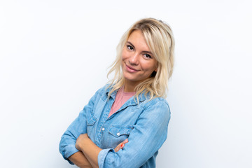 Young blonde woman over isolated white background with arms crossed and looking forward