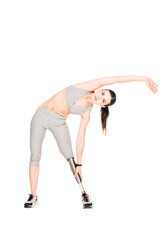 Fototapeta na wymiar full length view of disabled sportswoman with prosthesis stretching isolated on white
