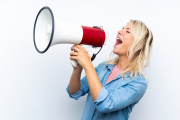 Young blonde woman over isolated white background shouting through a megaphone