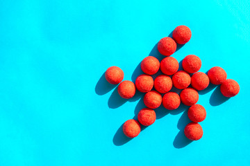 Star made of red sugary candies on turquoise background with copy space