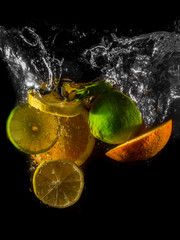 High-Speed Photo of Lemon, Lime and Orange Slices and Wedges Splashing into a Pool of Water - with a Black Background