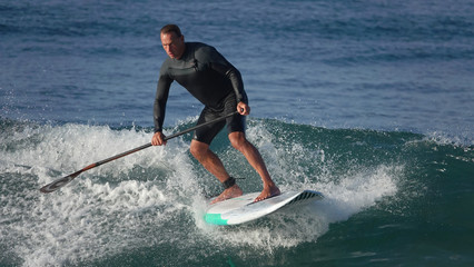 Paddle board surfer taking wave