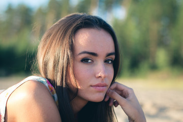 fashion outdoor photo of beautiful sexy woman with dark hair in light shirt relaxing at the beach.