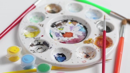 Rotating artist palette with dried paint, brushes and paint pots - Powered by Adobe