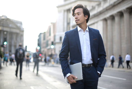 Elegant businessman walking in the street, wearing a blue suit