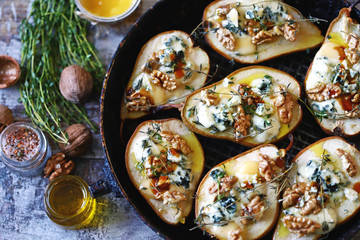 Halved Pears in a pan baked with Dorblu cheese, honey, walnuts and thyme. French cuisine. Keto diet. Selective focus. - obrazy, fototapety, plakaty