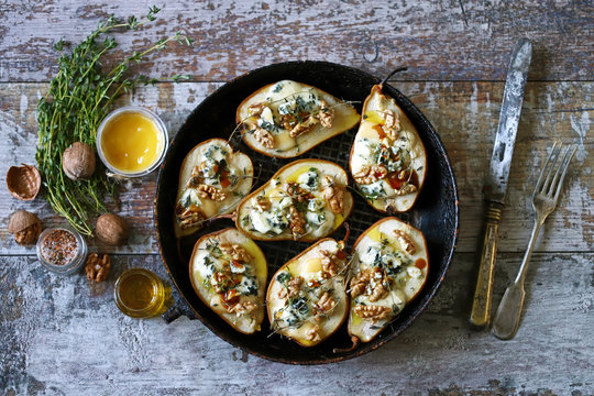 Halved Pears in a pan baked with Dorblu cheese, honey, walnuts and thyme. French cuisine. Keto diet. Selective focus.