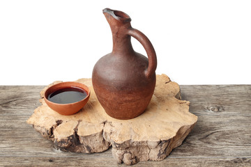 Wine jug and clay cup on the wooden table