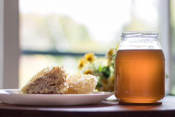 Fresh honey jar with flowers and honeycomb, delicious biological product.