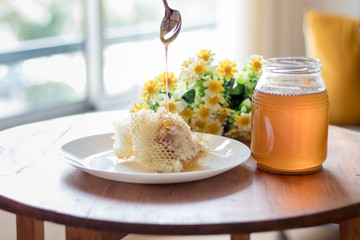 Fresh honey jar with flowers and honeycomb, delicious biological product.