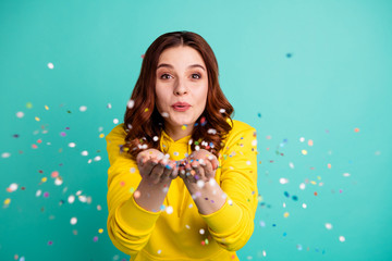 Photo of charming cute fascinating nice young girlfriend blowing confetti at you to show her festive mood with emotional face expression isolated over turquoise vivid color background - obrazy, fototapety, plakaty