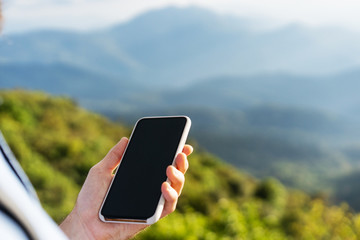 guy holding a phone in the mountains at sunset