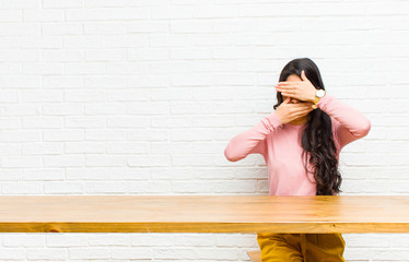 young  pretty latin woman covering face with both hands saying no to the camera! refusing pictures...