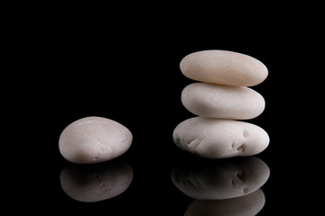 Fototapeta na wymiar Zen Stones. White stones piled on top of each other. White stones on a black background.