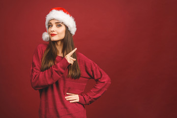 Christmas Santa hat woman portrait. Smiling amazed happy girl isolated against red background. Free copyspace for text. New year concept.