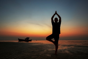 guy at sunset on the island practices yoga, silhouette