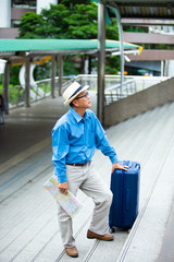 Portrait of happy senior mature man of travelers with luggage and map. Enjoying travel and happy tourism concept.