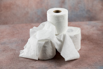 rolls oF soft toilet paper on a dusty pink cloth background