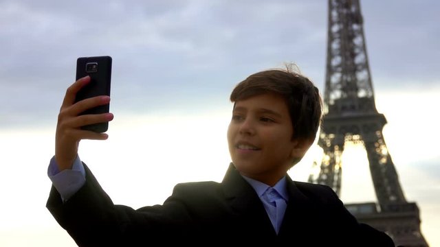 Handsome teenager boy makes selfie on the phone against the backdrop of the Eiffel Tower, Paris, France