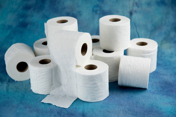 rolls of soft toilet paper on a luxurious aqua marine blue cloth background