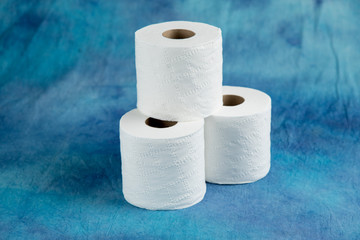 rolls of soft toilet paper on a luxurious aqua marine blue cloth background