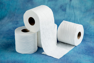 rolls of soft toilet paper on a luxurious aqua marine blue cloth background