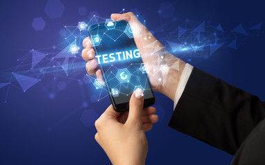 Female hand holding smartphone with TESTING inscription, modern technology concept
