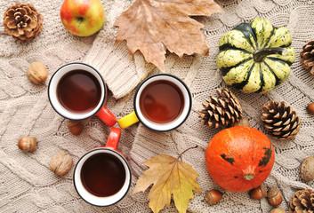 Autumn flat lay background. Pumpkins, apples, nuts,leaves, cups and sweater on wooden background.