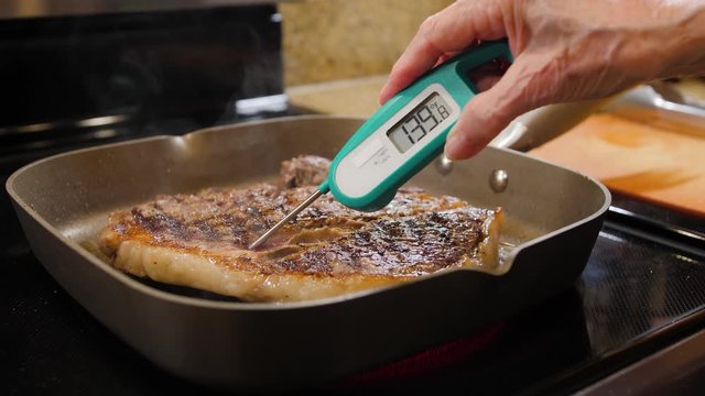 Checking For Safe Food Temperature With Digital Instant Thermometer. Cook Measuring Temperature Of Steak Cooked In Stove Top Grill Pan.