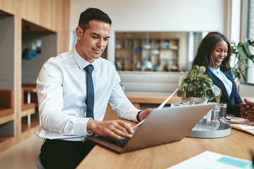 Smiling businessman working on his laptop in a modern office