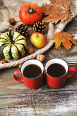 Autumn flat lay background. Pumpkins, apples, nuts,leaves, cups and sweater on wooden background.