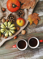 Autumn flat lay background. Pumpkins, apples, nuts,leaves, cups and sweater on wooden background.