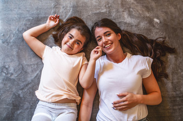 Portrait of mother and daughter lying on bed and looking at camera.