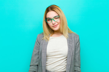young pretty blonde woman looking happy and friendly, smiling and winking an eye at you with a...