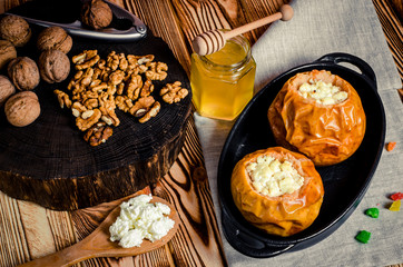 healthy food. Baked apples with cottage cheese and nuts lie in a black baking dish on a wooden table