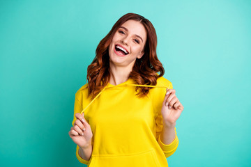 Photo of cute attractive nice beautiful white girlfriend beautiful playing with her hoodie smiling toothily laughing with good mood isolated over turquoise bright color background