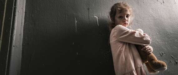 panoramic shot of upset kid standing with soft toy, post apocalyptic concept