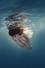 Girl in white swims underwater