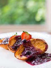 Close up of french toast with rasberry sauce on white plate